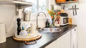 A compact kitchen with a washing machine, a microwave, and a sink.