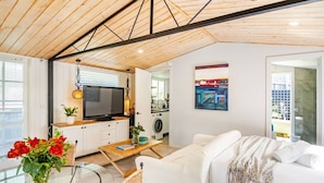 Ein modernes Wohnzimmer mit Fernseher, einem Essbereich mit Glastisch und einer gemütlichen Sitzecke mit Sofa.