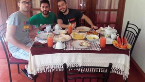 Three people seated at a table with various dishes, drinks, and a teapot. - Thathsara Holiday Inn (Sigiriya,)