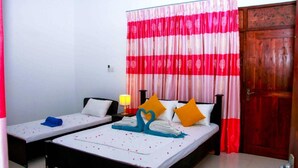 A room with two single beds, a wooden door, and a curtain with a red and white pattern. - Thathsara Holiday Inn (Sigiriya,)
