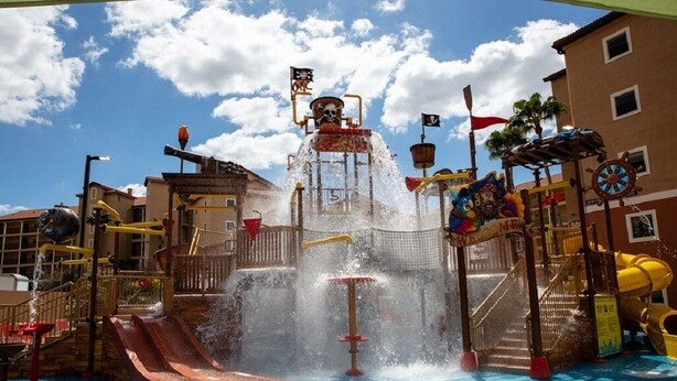 Parque acuático con fuente central, toboganes y zona de juegos temática de piratas.