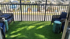 Een balkon met uitzicht op een jachthaven, zitplaatsen buiten en een zwembad.