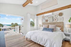 A bedroom with a large bed, a balcony with a view, and various wall decorations. - 45 sec to Beach Access • Gulf Views • Pool+Spa • Bikes+Putting Green ... (Anna Maria)