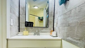A bathroom with a white vanity, a mirror, and three hanging lights. - Sun & Sand condo retreat (Panama City Beach)