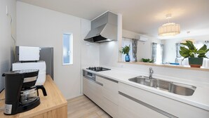 A modern kitchen with a built-in dishwasher, a coffee maker, a stainless steel sink, and a large window with curtains.