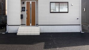A two-story building with a flat roof, a front door, and two windows on the upper floor.