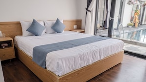 A modern bedroom with a wooden bed, white bedding, and a view of a swimming pool. - T&H Hoi An Beach Villa (Da Nang)