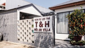 A sign for a hotel named "DICH VU LUU TRU T&H HOI AN VILLA" with contact numbers. - T&H Hoi An Beach Villa (Da Nang)