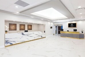 Eine moderne Hotelrezeption mit Marmor-Tresen, einer Oberlichter und einem Schild mit der Aufschrift 'WENTILATE PALACE'.