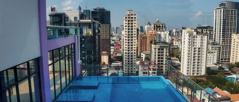 Una piscina en la azotea con vistas a la ciudad, rodeada de edificios altos.
