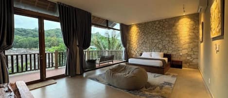 A bedroom with a stone wall, a bed, a bean bag, and a view of the outdoors.