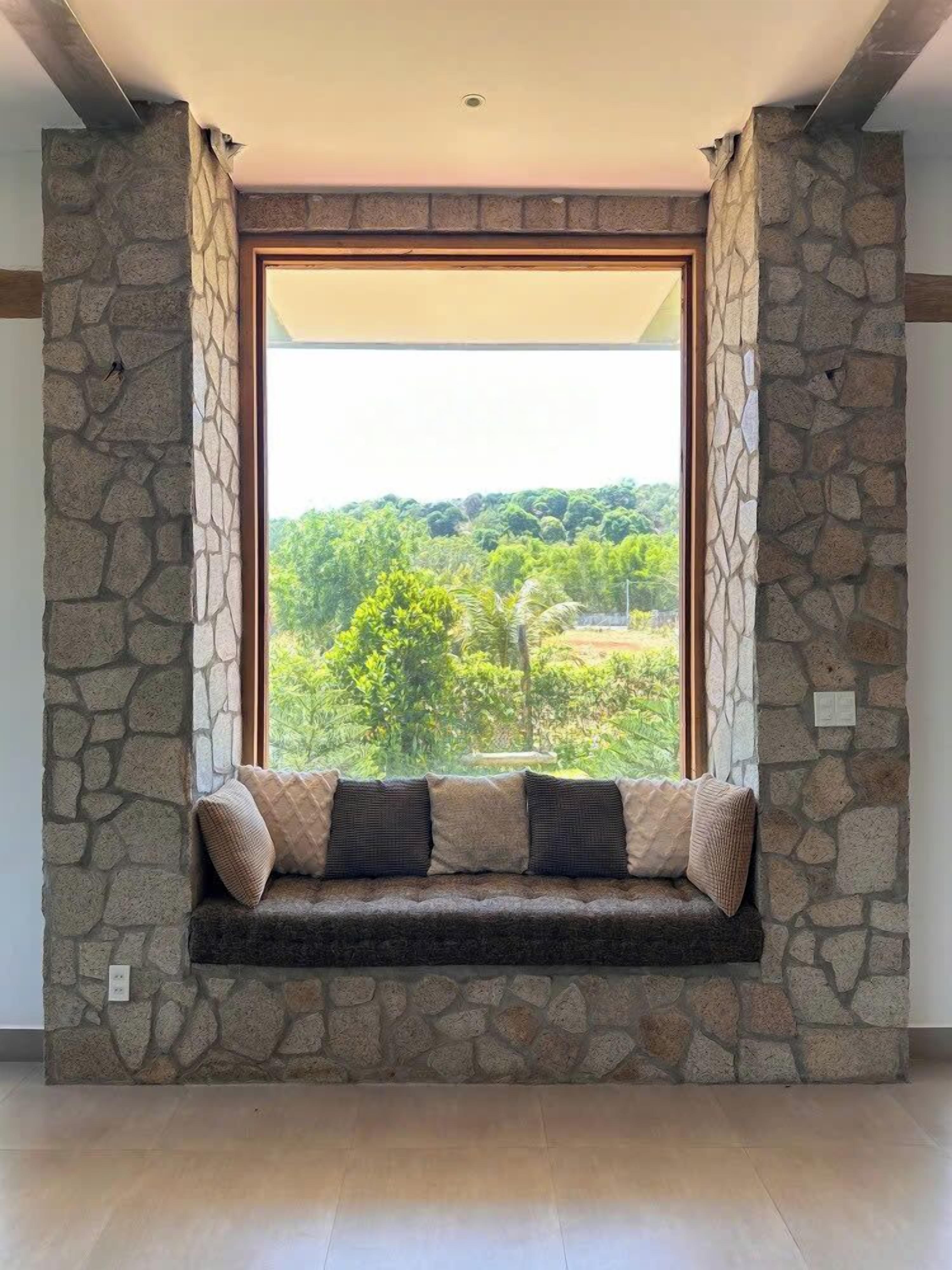 A stone-walled room with a large window overlooking a green landscape.