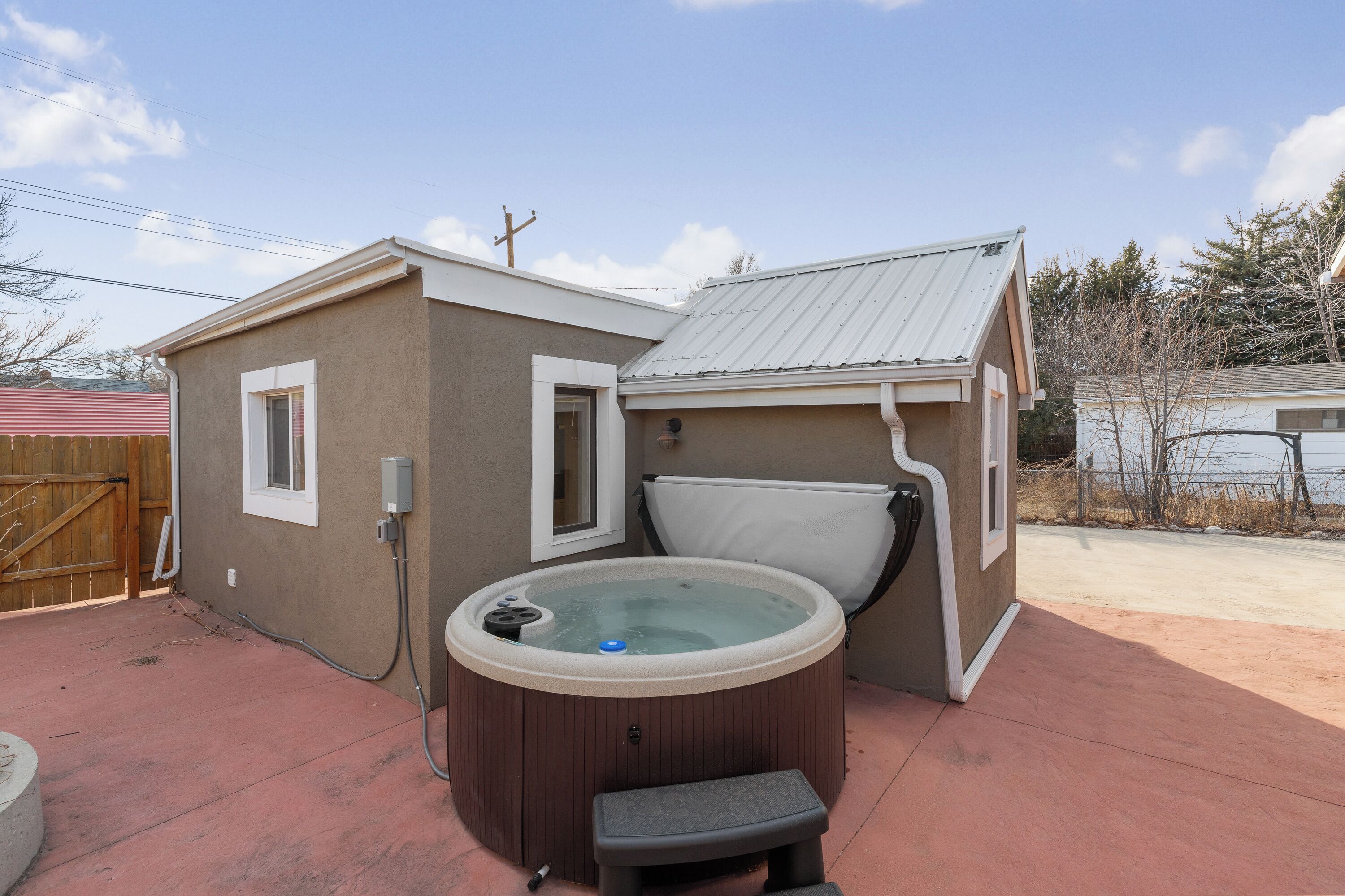 A hot tub attached to a house with a covered patio area.