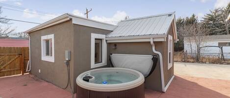 A hot tub attached to a house with a covered patio area.