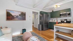 A modern kitchen with green cabinets, stainless steel appliances, and a wooden dining table.