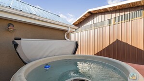 A hot tub with a control panel, a white towel, and a wooden fence in the background.