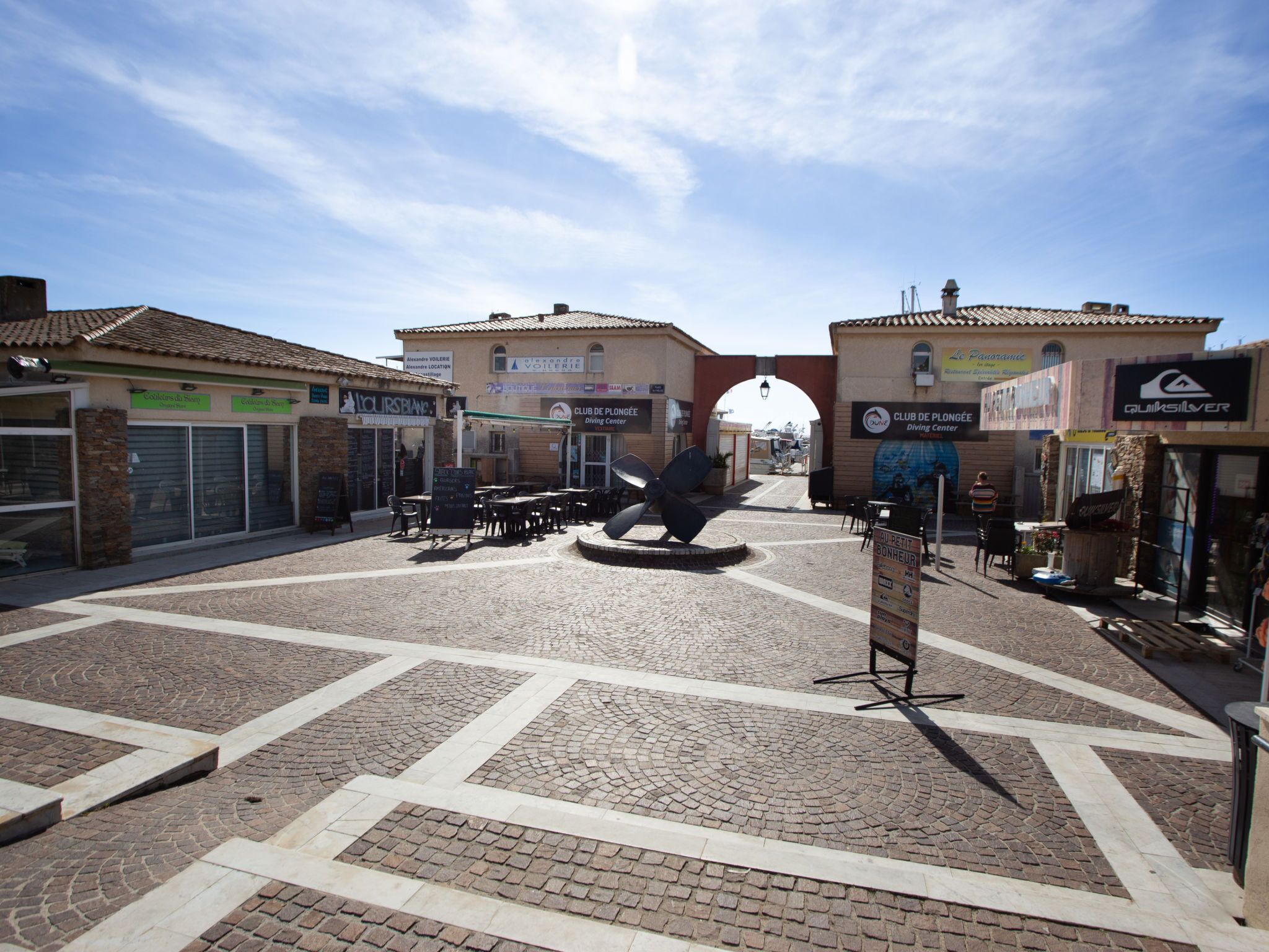 Una plaza empedrada con tiendas y un centro de buceo.