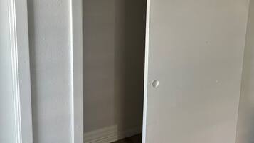 A white closet with a sliding door, a visible shelf, and a dark-colored hanging garment.