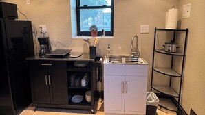Une cuisine de taille réduite, dotée d’une fenêtre, d’un évier, d’une cuisinière et d’un petit placard.