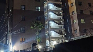 Un hotel de varios pisos con señalización iluminada, balcones y una valla de alambre de púas.
