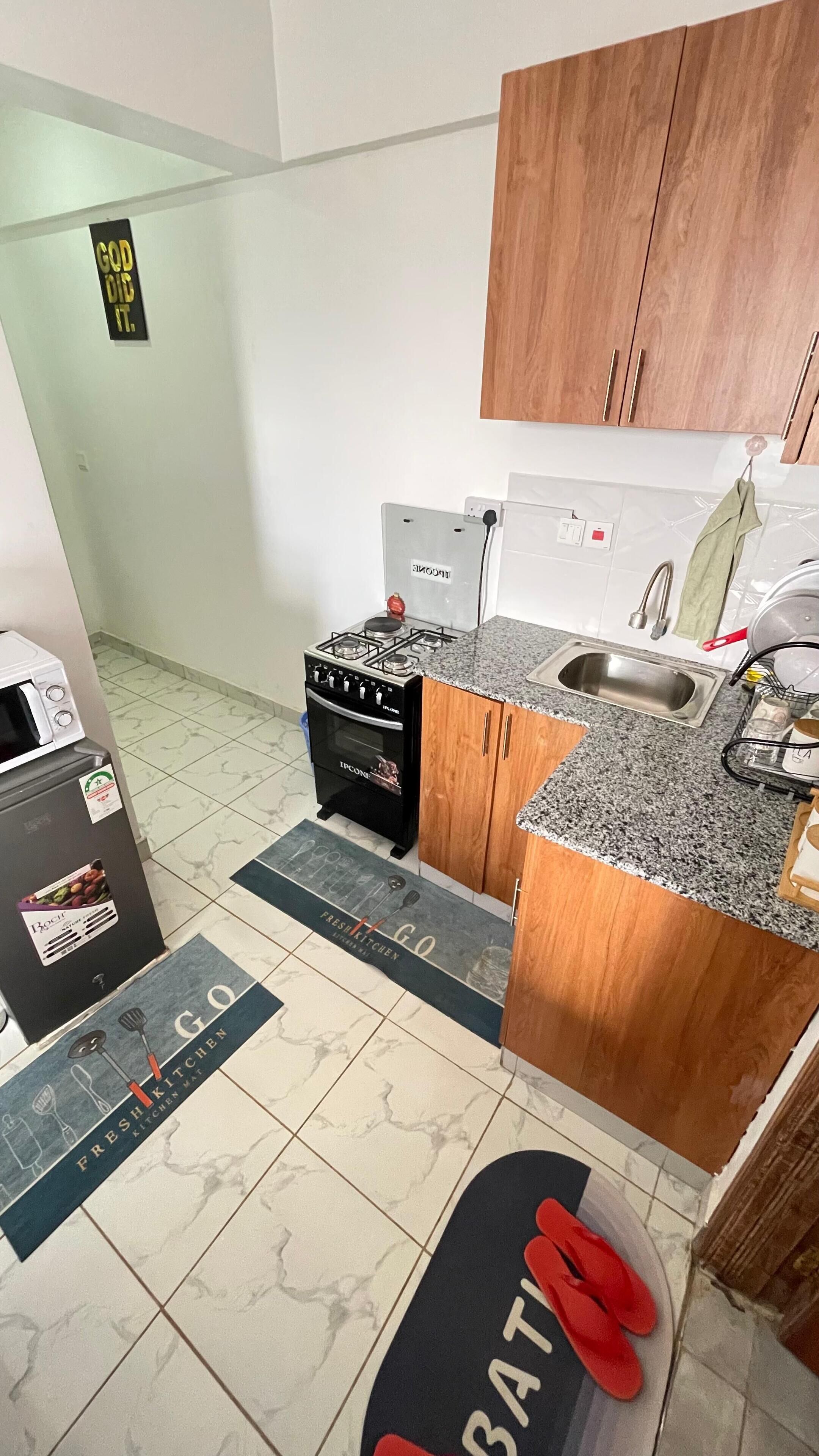 Una cocina compacta con estufa a gas, horno y pileta. Incluye un refrigerador, un microondas y una pequeña mesada.