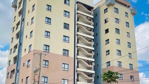 Un edificio residencial de varios pisos con balcones, un tanque de agua visible y un acceso con portón.