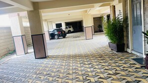 Un área de estacionamiento techada con piso estampado y pilares, que conduce a la entrada de un edificio.