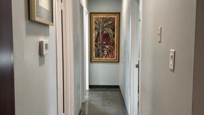 Ein Flur mit Türen an beiden Seiten, einem Deckenlüfter und einem großen, gerahmten Gemälde an der Wand.