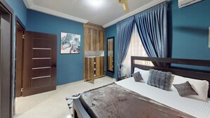Een slaapkamer met een bed, een kledingkast, een spiegel en een raam met gordijnen.