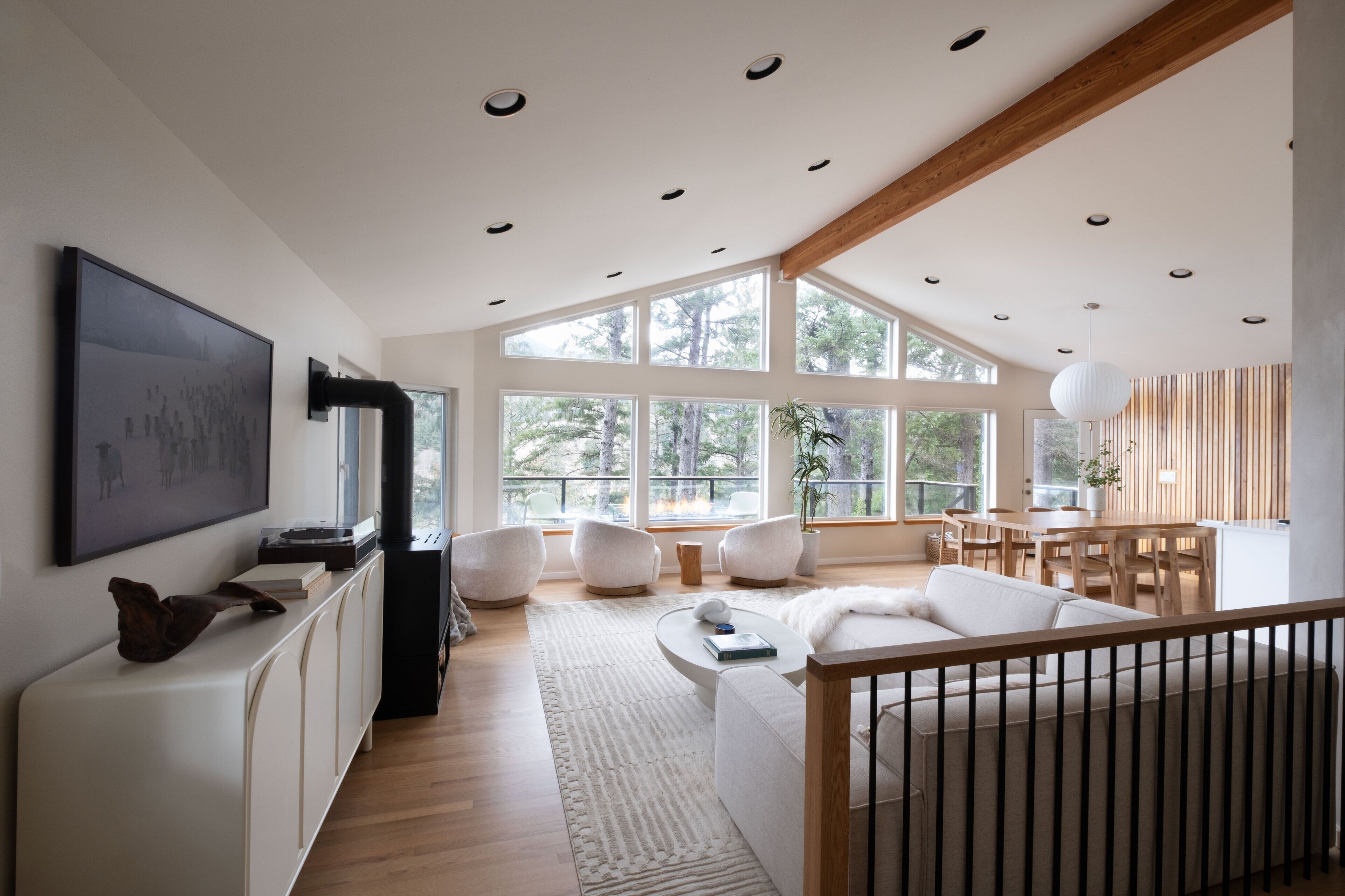 A modern living room with a large window, a fireplace, and a dining area.
