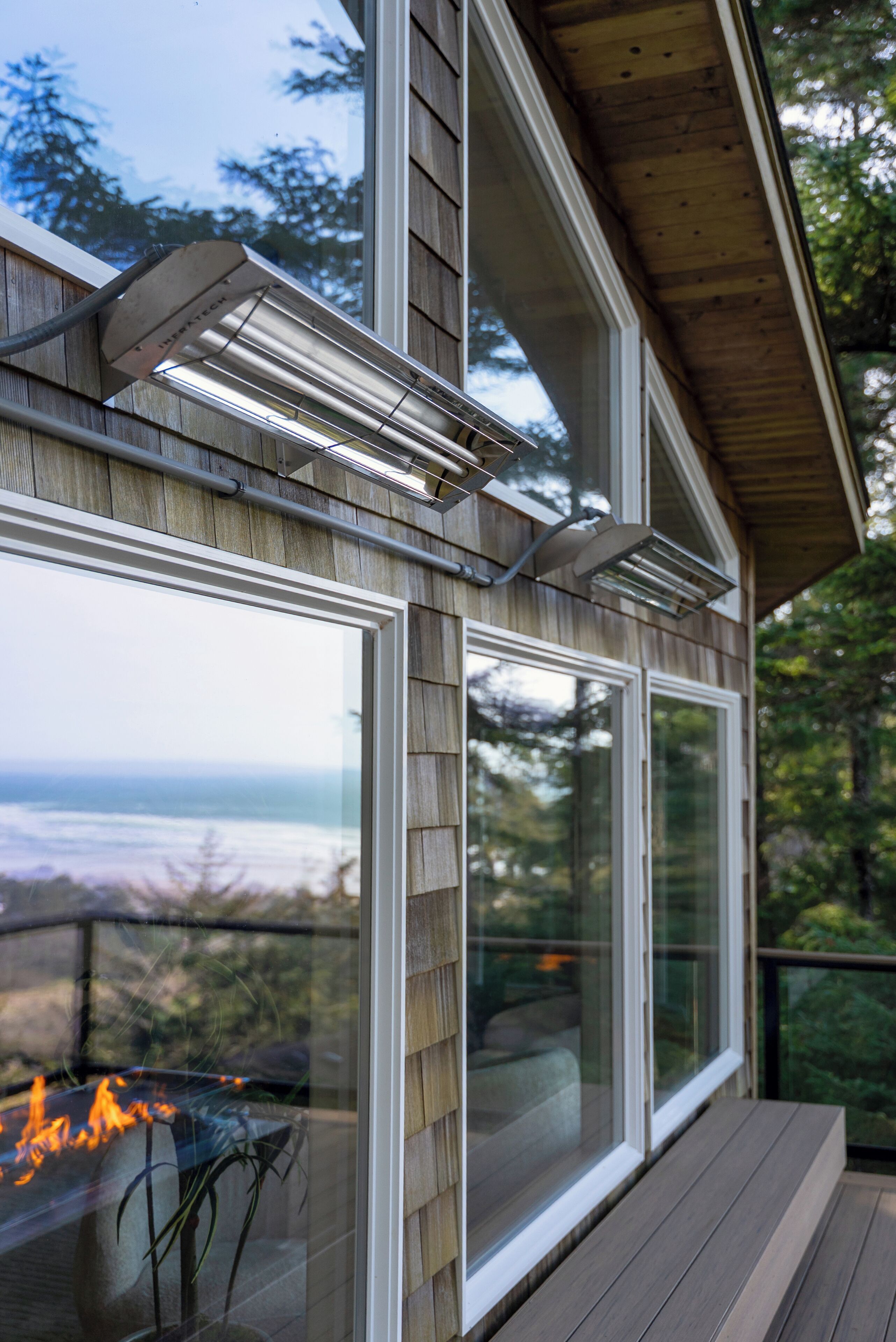 A modern house with large windows, a deck, and a fire feature.