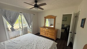 Une chambre à coucher avec un lit, une commode, un ventilateur de plafond et une vue par la fenêtre.