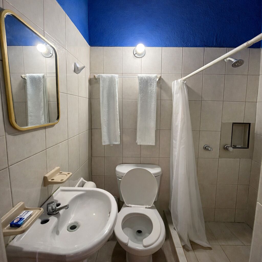 Un baño con lavamanos, inodoro, ducha y espejo.