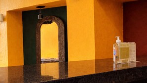 Un baño con encimera negra, pared amarilla y espejo con marco de madera.