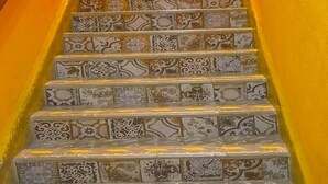 Una escalera con baldosas estampadas y una pared amarilla.