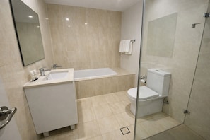 Un baño moderno con lavamanos, bañera, inodoro y cabina de ducha de vidrio.