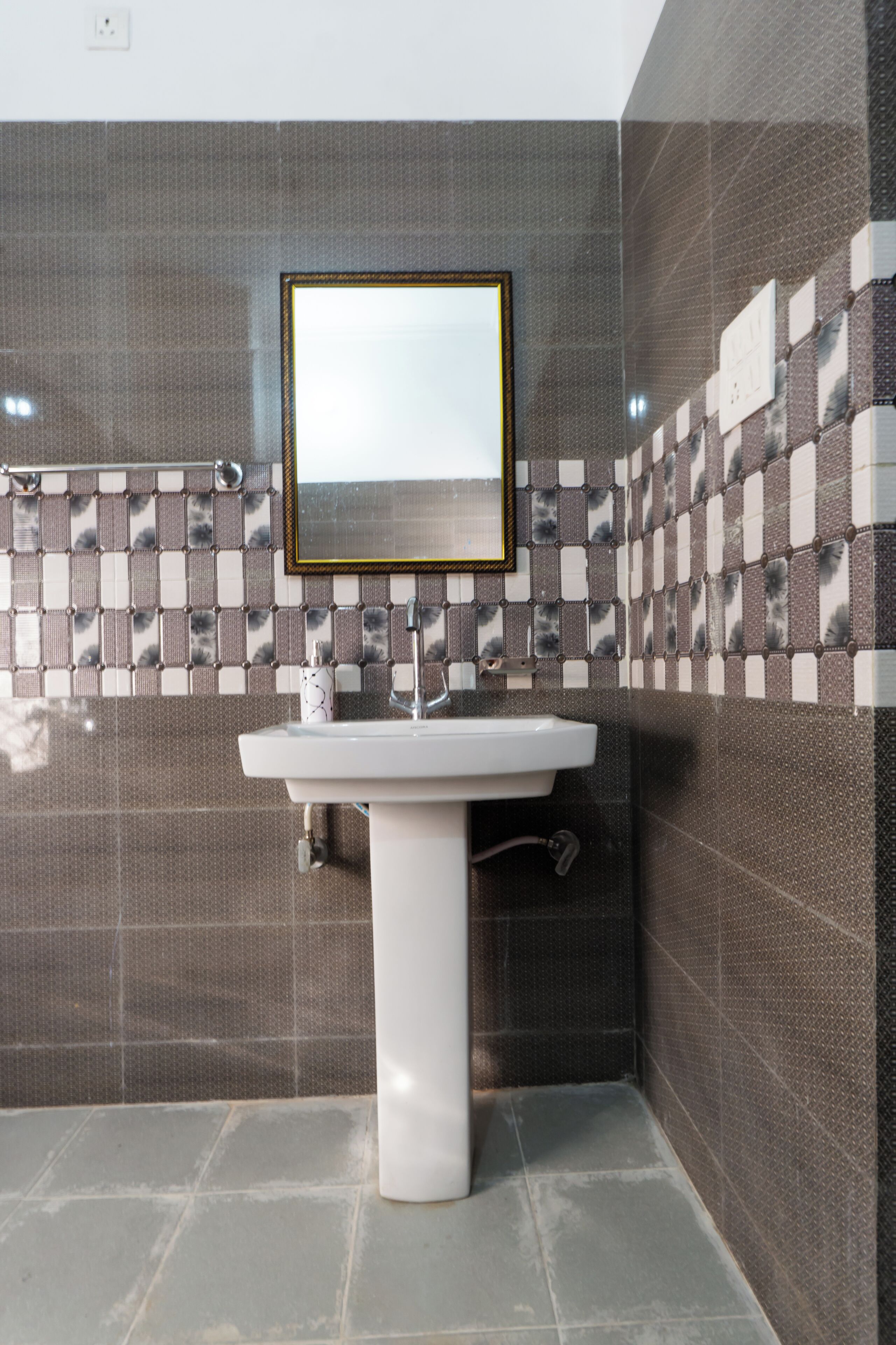 A bathroom with a white sink, a mirror, and patterned tiles on the walls.