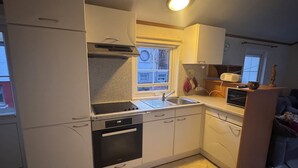 A compact kitchen with white cabinets, a built-in oven, a sink, and a microwave.