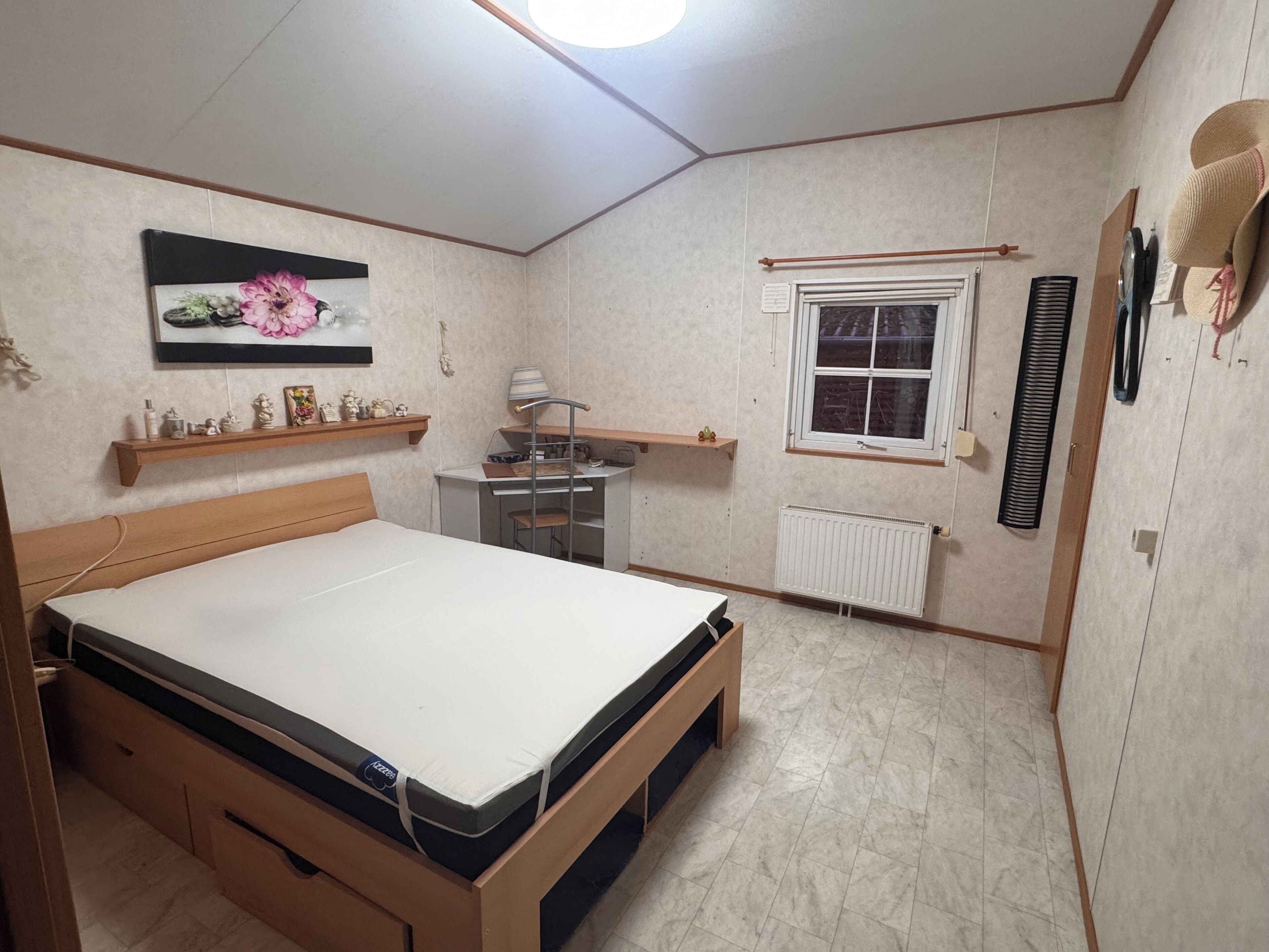 Une chambre à coucher avec un lit, un petit bureau, un radiateur et une fenêtre.