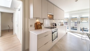 A modern kitchen with white cabinetry, a built-in oven, and a large window providing a view of the outdoors. - Montague Street (Dublin)