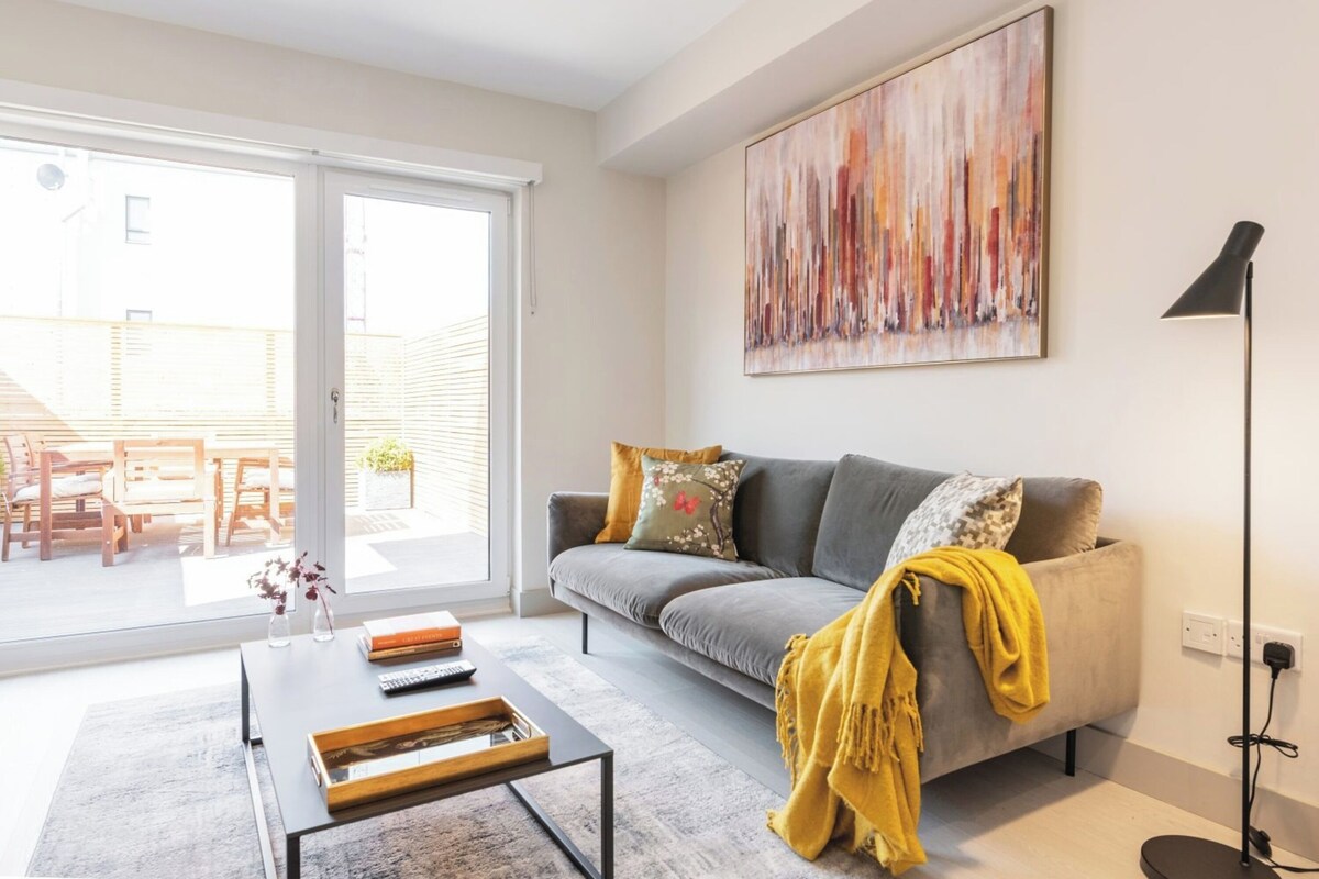 Ein Wohnzimmer mit grauem Sofa, einem Couchtisch und einem großen, abstrakten Gemälde an der Wand.