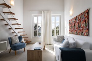 Ein modernes Wohnzimmer mit Treppe, Sofa, Couchtisch und einem großen abstrakten Gemälde.