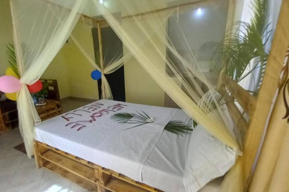 Une chambre avec un lit sous un dais, une table de chevet en bois et une petite table décorée de ballons.