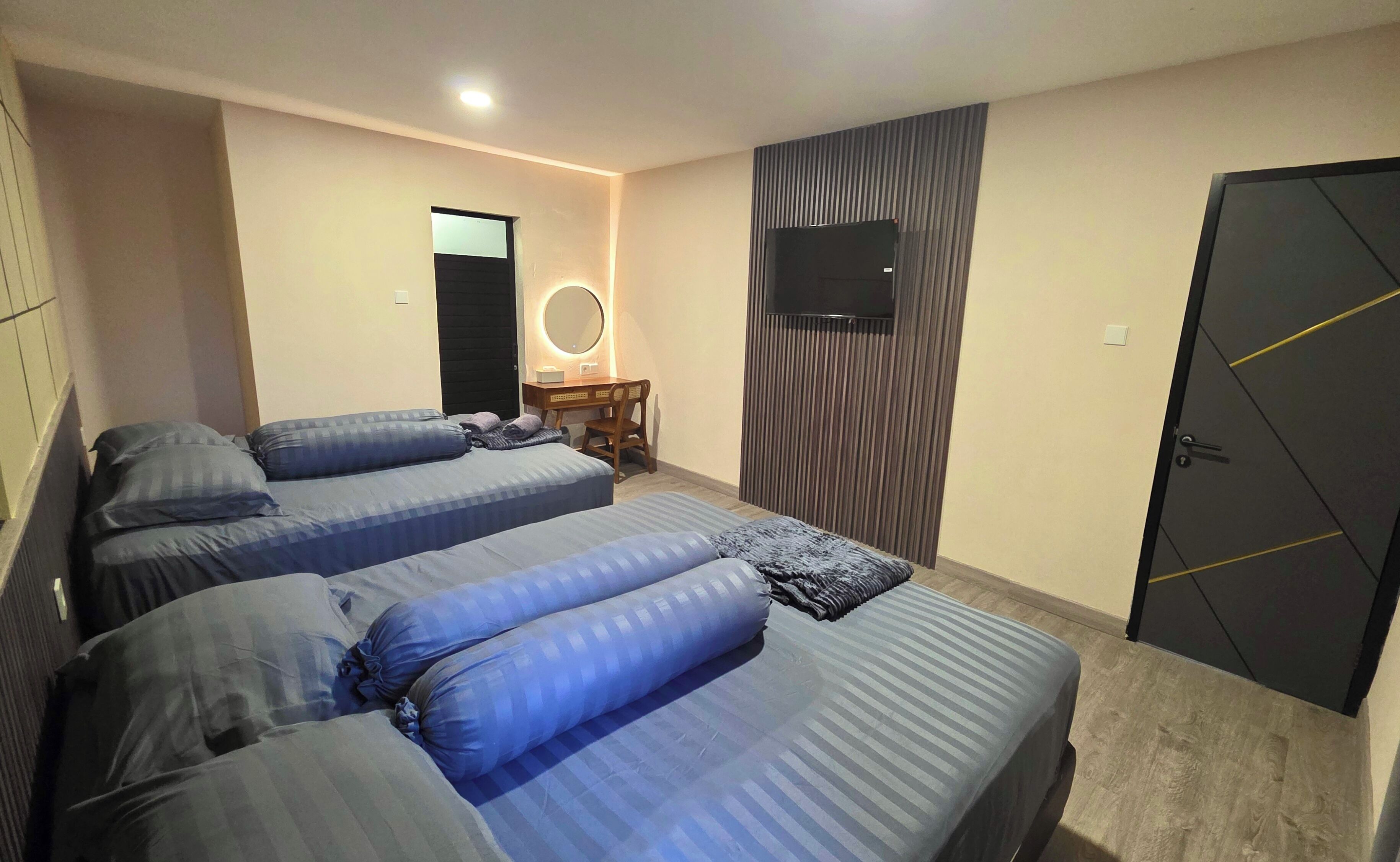 A hotel room with two beds, a desk, a mirror, a TV, and a wardrobe.