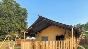 A wooden cabin with a sloped roof, a balcony, and a swing set.