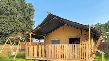 A wooden cabin with a sloped roof, a balcony, and a swing set.