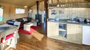 A cozy living area with a fireplace, wooden furniture, and a kitchen with modern appliances.