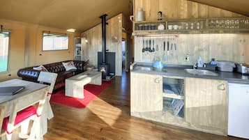 A cozy living area with a fireplace, wooden furniture, and a kitchen with modern appliances.
