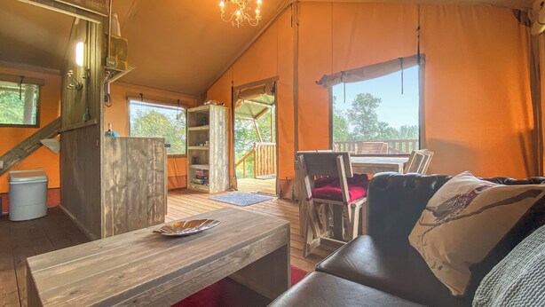 A cozy cabin interior with a wooden table, a leather sofa, and a bookshelf.