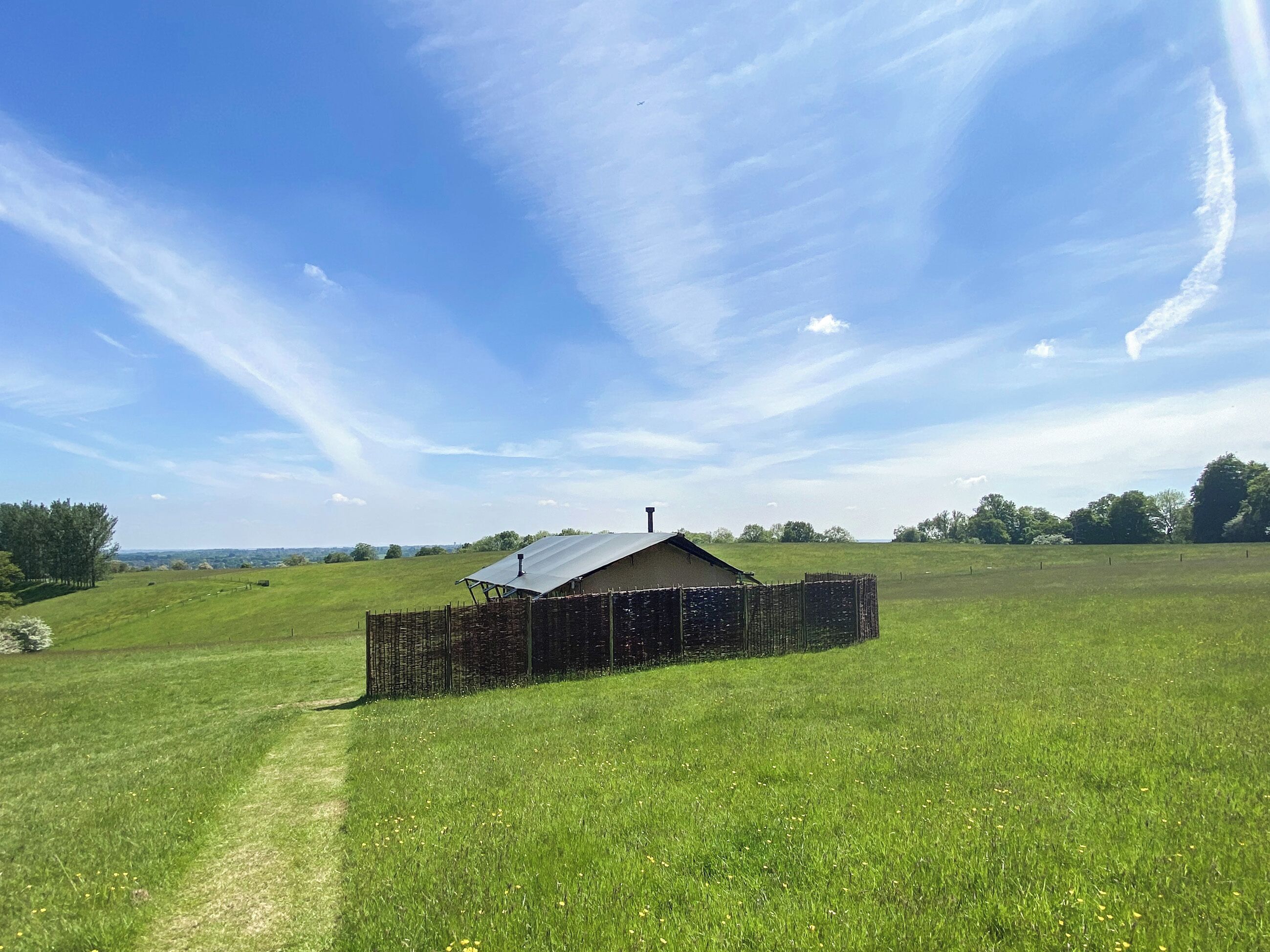 Een landelijk landschap met een gebouw, een omheind gebied en een heldere lucht.